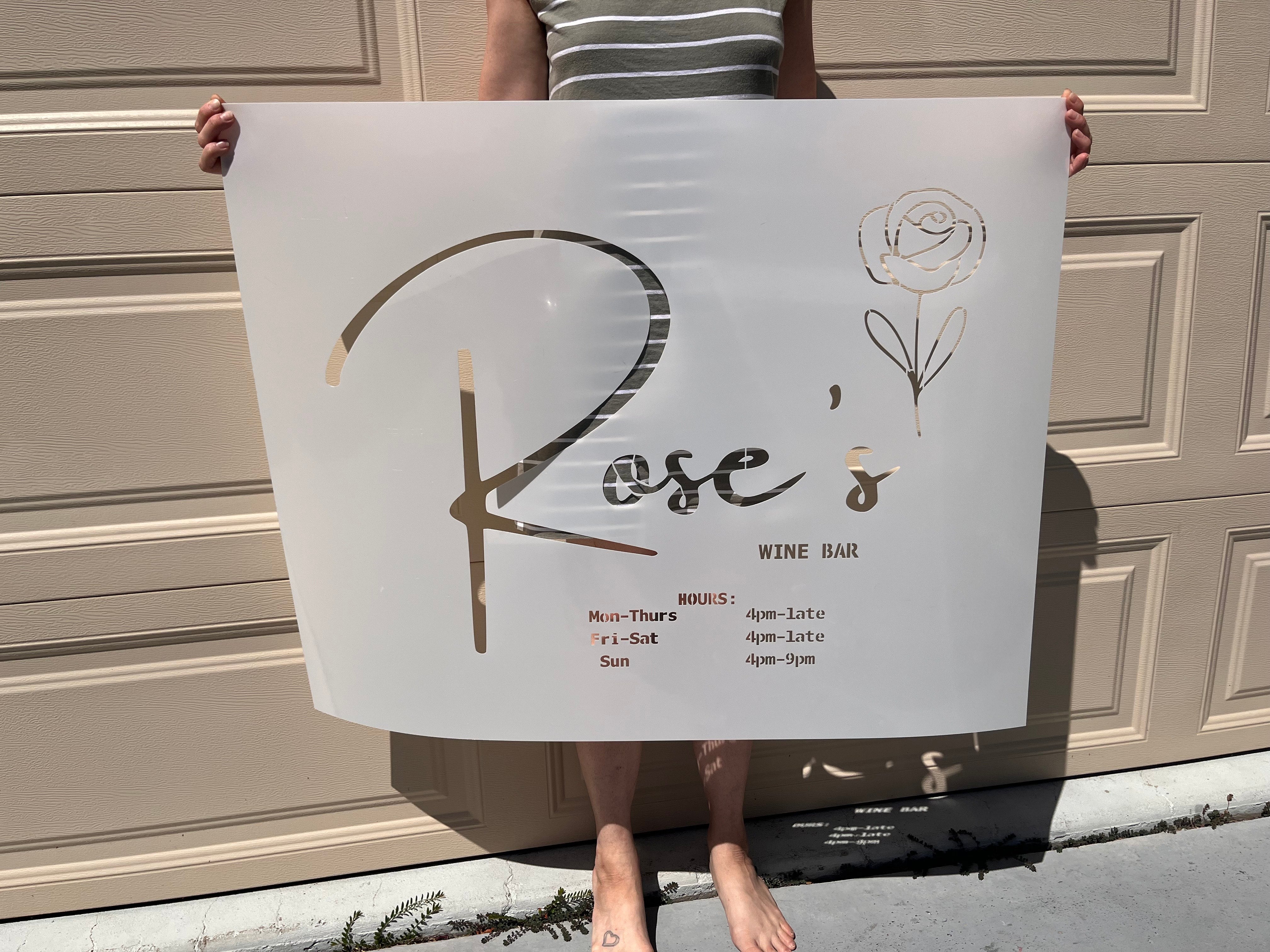 Custom laser-cut stencil for Rose's Wine Bar logo and operating hours sign, ideal for storefront window painting and branding.